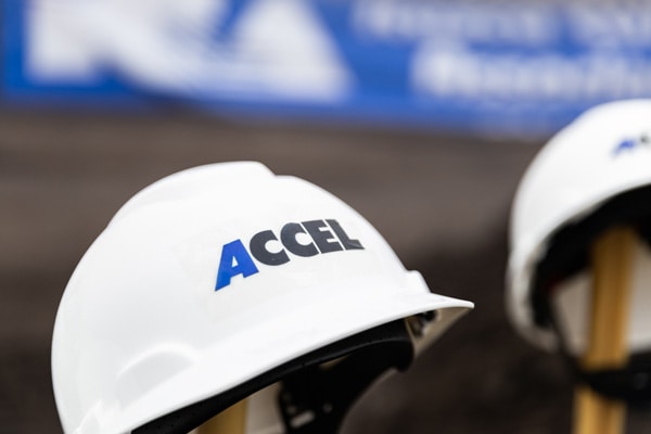 A white Accel hardhat sitting on a shovel handle.