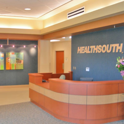 Interior image of the reception area at HealthSound Rehabilitation Hospital. The walls are blue the desk is brown.