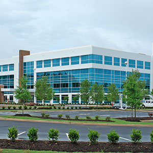 Photograph of the St. Francis Millennium building featuring shrubs around the parking lot area.